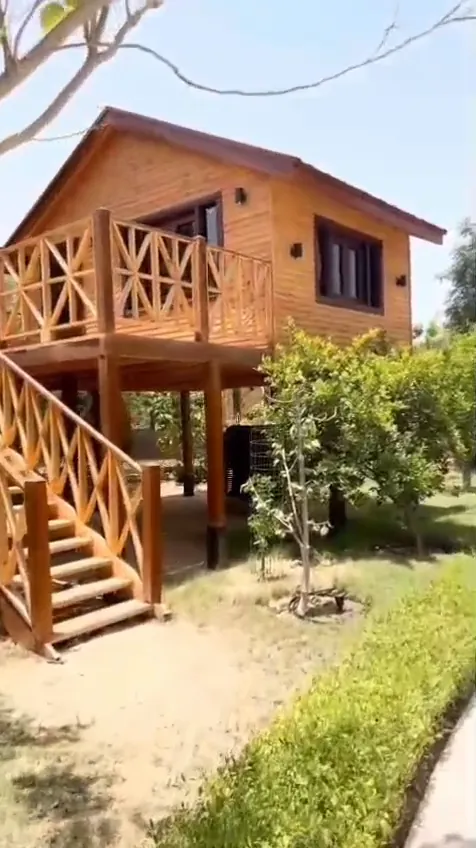 Dış merdiveni ve ahşap korkuluklu verandası bulunan yükseltilmiş ahşap ev
