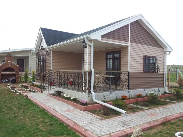 Verandalı ve yatay cephe kaplamalı tek katlı yapı, bahçe yolu ve çim alan