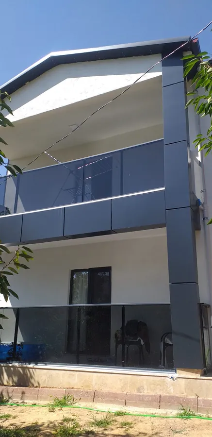 Gri ve beyaz yüzeylerin birlikte kullanıldığı balkonlu yapının dış cephe görünümü