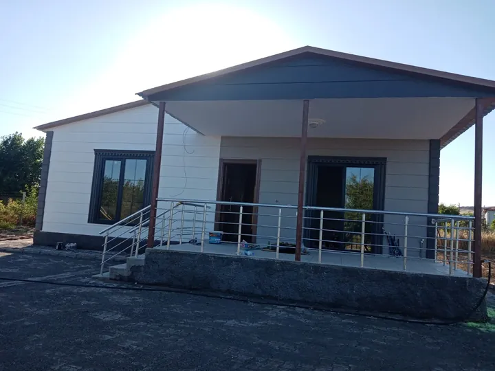 Ön verandası ve metal korkulukları bulunan tek katlı müstakil yapı