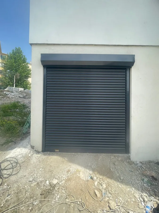 Yapı giriş açıklığına monte edilmiş koyu gri panjur