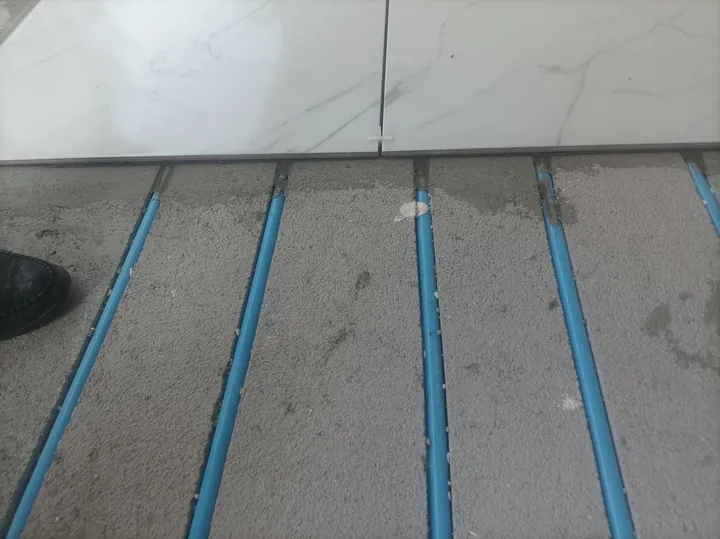 Zemine açılan kanallar içindeki mavi borular ve seramik kaplamanın birleşim detayı